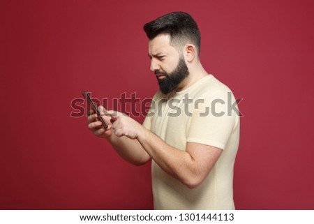 The young pretty cute brunette with a beard emotionally writes a message in the phone