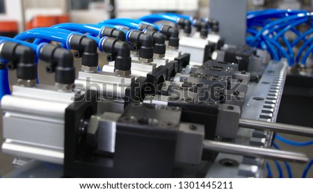Pneumatic compact air cylinders with air or water elbow fitting connected air or water hoses.Selective focus Royalty-Free Stock Photo #1301445211