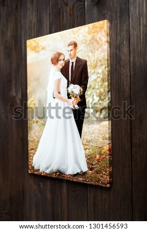 Photo of a wedding couple printed on canvas. Photography stretched on a wood stretcher bar on a brown wall background. Sample gallery stretch