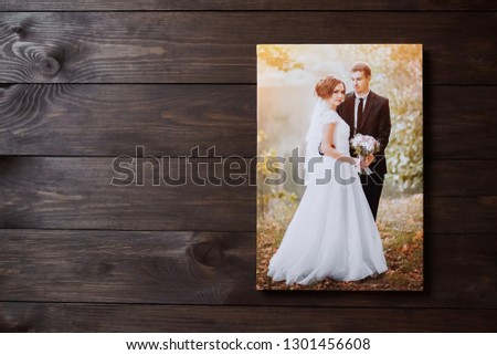 Photo of a wedding couple printed on canvas. Photography hanging on a wooden wall background with copy space