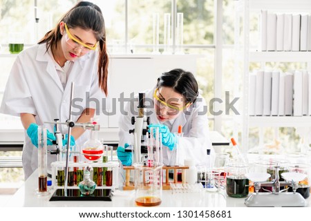 Group of chemists working in a lab. Young asian female chemists with senior caucasian chemist working together in lab, looking into microscope. Science concept. Royalty-Free Stock Photo #1301458681