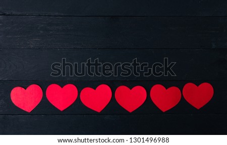 Red hearts on black wooden background. Place for text, copy space