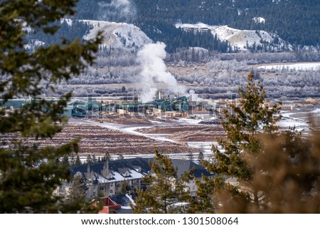 Aerial citycape view of Radium Hot Springs, British Columbia Canada in the winter, with a natural frame on housing and the lumber mill Royalty-Free Stock Photo #1301508064
