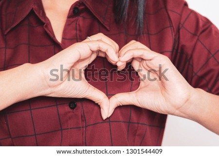 Young beautiful woman smiling in love showing heart symbol and shape with hands wearing red dress. Romantic concept on white background.