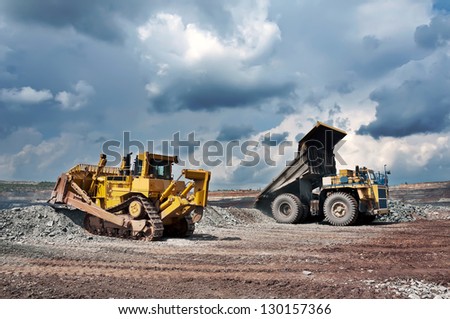 A picture of a big yellow mining truck and bulldozer at worksite