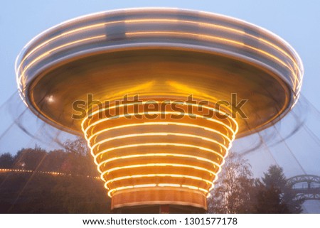 A blurry colorful chain carousel in motion at the amusement park, evening illumination. The effect of bokeh and long exposure