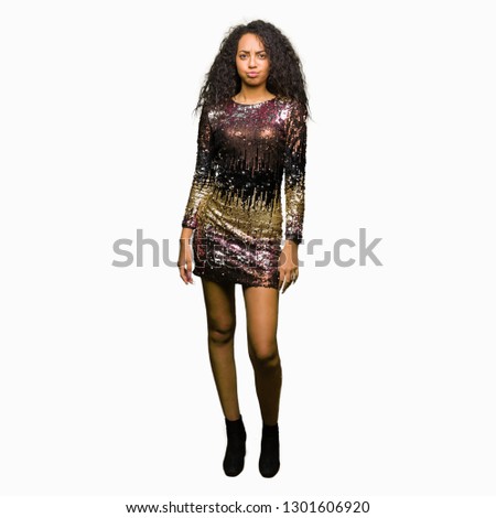 Young beautiful girl with curly hair wearing night party dress puffing cheeks with funny face. Mouth inflated with air, crazy expression.