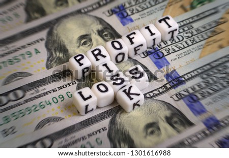 Profit or Loss, or Risk concept with letter cubes on a dollar bank notes. 