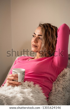 Beautiful casual girl lying in bed and enjoying in coffee at home
