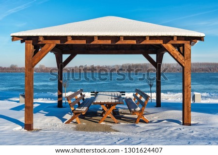 Table and benches on the snow covered river with a beautiful view.