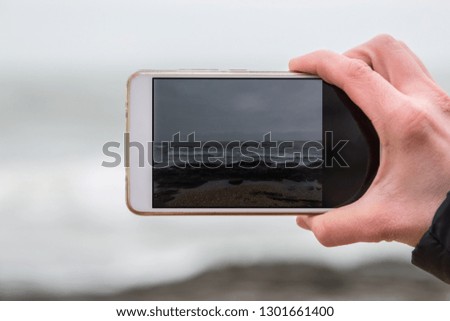 Woman hand taking photo of the sea with a smartphone.