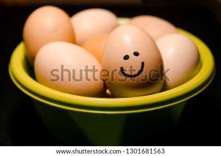 Smiling egg on top of lots of fresh chicken eggs in the green basket from the top view. Show your emotions. Organic food ingridients close up. Stay healthy concept.