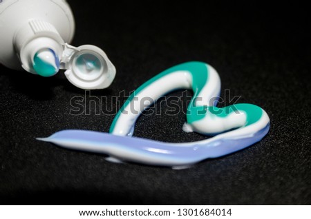 White and blue toothpaste in the shape of the heart. Squeeizing the  tooth tube and cleaning teeth concept. Morning routine. 