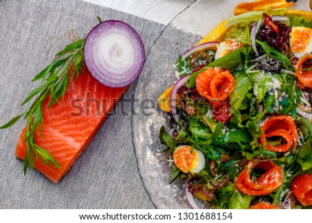 fresh salad with vegetables, greens and red fish with caviar served on the table, healthy food