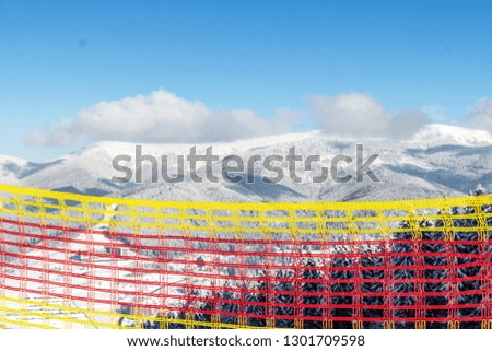 
Ski resort Bukovel. Ukrainian Carpathians. Safety fence for security. Multicolored mesh to attract attention. The rules of skiing and snowboarding. Warning of danger. Winter landscape.