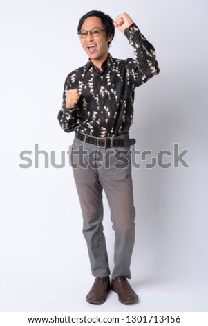 Full body shot of excited Japanese businessman with fists raised