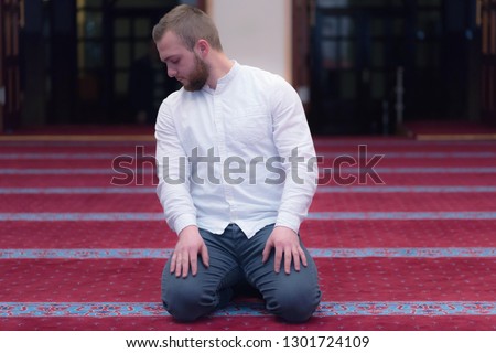Young religious european muslim man praying inside the beautiful big mosque.