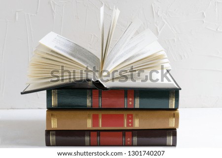 Education and reading concept, open book on a stack of books, selective focus on the white background