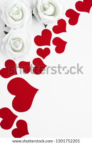 Top view of romantic decoration from red hearts and white roses on white background as a frame for copy space. Happy Valentines. Mothers or Womens Day beautiful vertical card.