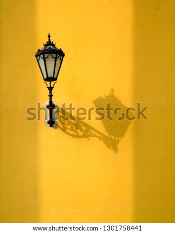 Wall lantern on yellow stucco with dramatic shadows on the Cathedral Basilica of St. John the Apostle in Eger, Hungary