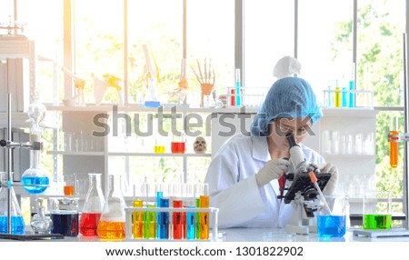 The woman scientist doing experiment using microscope in laboratory. Photo concept of Medical healthcare technology and pharmaceutical research and development.