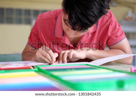 Young man drawing a picture with color pencils. Selective focus.