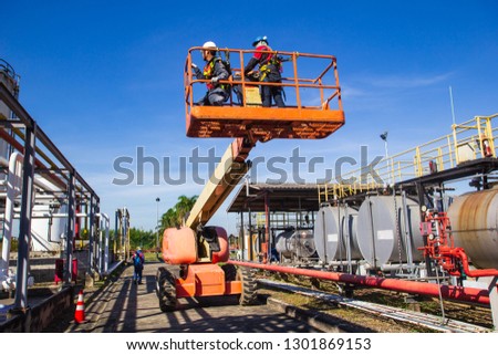 Two male  industry working at high in a boom lift  inspection of pipeline oil