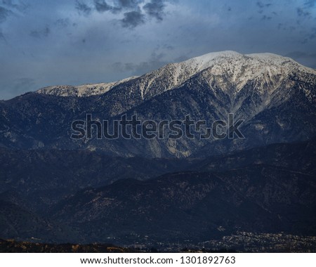 A snow covered mountain surrounded by clouds.  This is Mt Baldy near Los Angeles in Southern California. Also known officially as Mt San Antonio, this peak reaches to 10,064 feet above sea level.