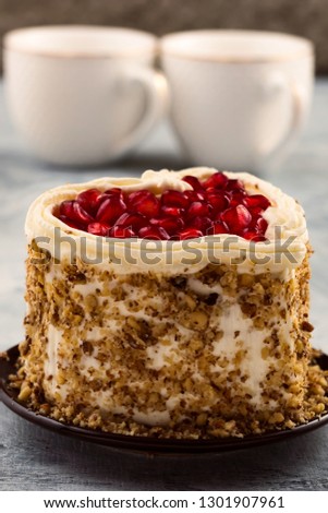 A piece of heart-shaped cake with pomegranate and nuts.