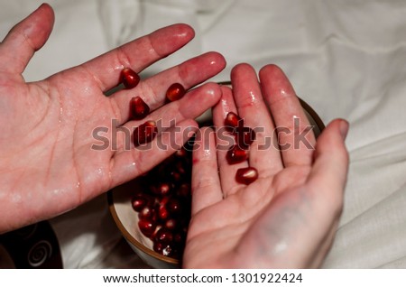 Dirty human hands in the pomegranate juice. The background is white. Ripe organic food close up. Stay healthy concept.