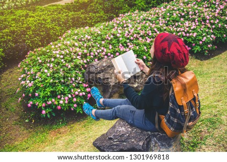 woman travel nature in the flower garden. relax sitting on rocks and reading books In the midst of nature at national park doi Inthanon.