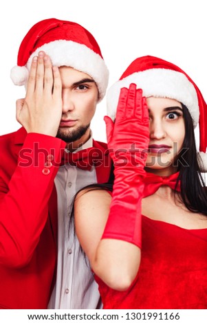 young couple having fun at a christmas theme party. young man and woman in red suits with Santa hats. isolated on white