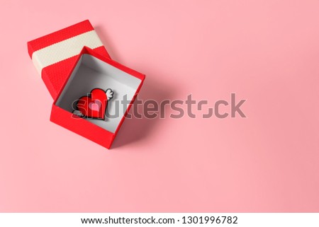 Нeart in a red gift box on a pastel pink background. February 14 card, Valentine's day. 8 March, International Happy Women's Day. Flat lay, top view, copy space 