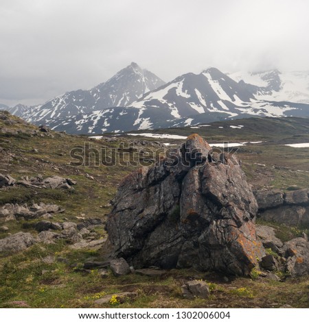 A deserted and moody landscape high in the alpine mountains of the rockies. A big rock stand out the picture with similarity of the peaks in the background
