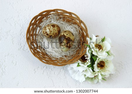 quail eggs in a nest on a white textured background. Happy Easter. Basket with eggs and flowers