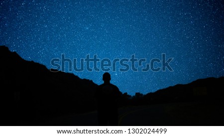 Silhouette of man and mountains stares at star filled sky