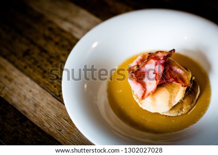 Pancakes, bacon and syrup served in large plate on wooden table