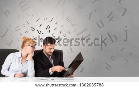 Business person sitting at desk with editorial and letters concept