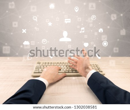 First person view of hand typing with social media concept icons around