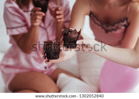 Close up photo. Bachelorette party in the bedroom. Delicious looking chocolate cookies at the girlish day. Four women in night wear.