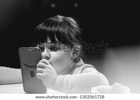 Young pretty kid holding a smartphone in her hands and watching cartoons 