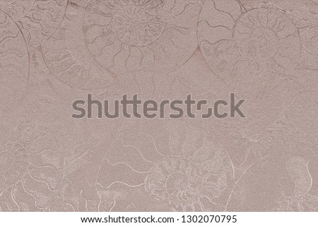 Pale pink nacreous color of abstract background of fossil Ammonites, Ammonoidea. Decorative pearl wallpaper of petrified shells. Print from textured spirals of seashells on light beige backdrop.