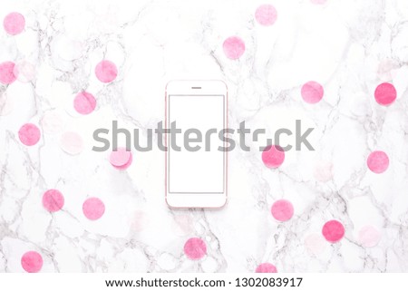 Mobile phone with pink decorations on a marble background top view