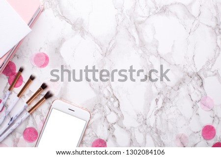 Cosmetic brushes and mobile on a marble background