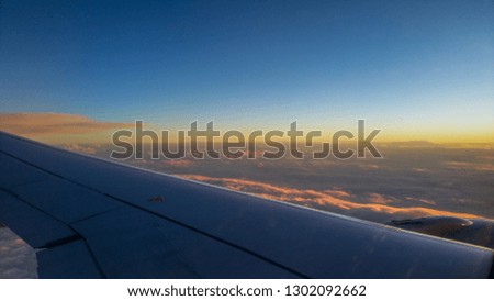 Aircraft over the sunset sky. Beautiful sunset sky above clouds with dramatic light. Amazing view from airplane. 