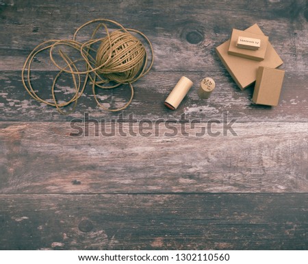 Artistic crafting supplies and art tools of hemp yarn, natural cardboard boxes and stamps for creative homemade gift wrapping and handmade crafts, on wood background with copyspace