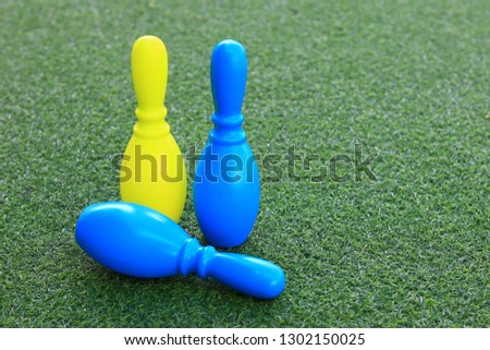 Blue and yellow plastic bowling pin toys on the green grass.