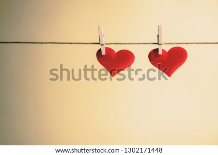 Two adorable red hearts side by side hanging from a string by wooden pegs. Romantic Valentine's Day with copy space. Royalty-Free Stock Photo #1302171448