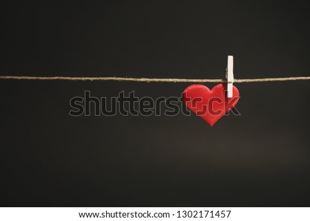 A single adorable red heart hanging from a string by white clothes peg. Romantic Valentine's Day scene with copy space. Royalty-Free Stock Photo #1302171457
