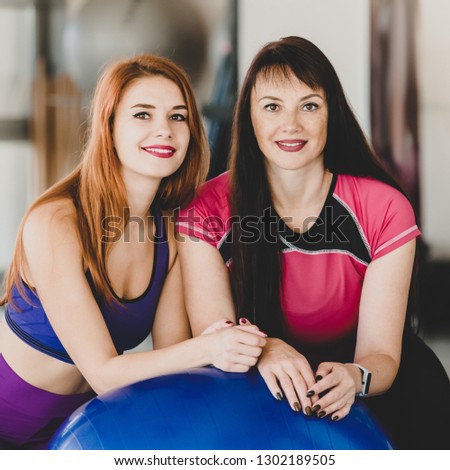 Portrait of cheerful smiling mother and daughter with fitness ball